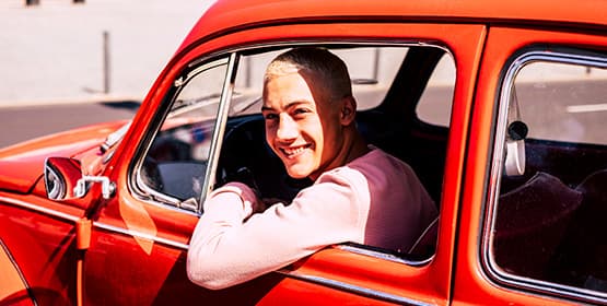 Young person leaning out of an old car window