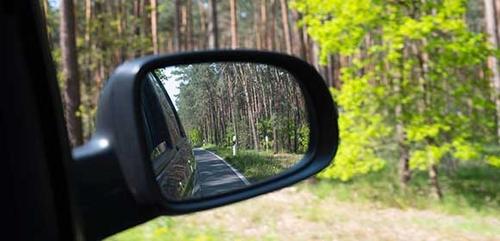 photograph of car wing mirror driving down country road