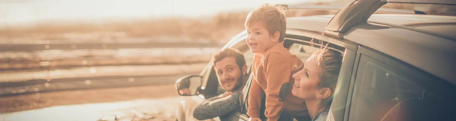 Young family leaning out of car windows