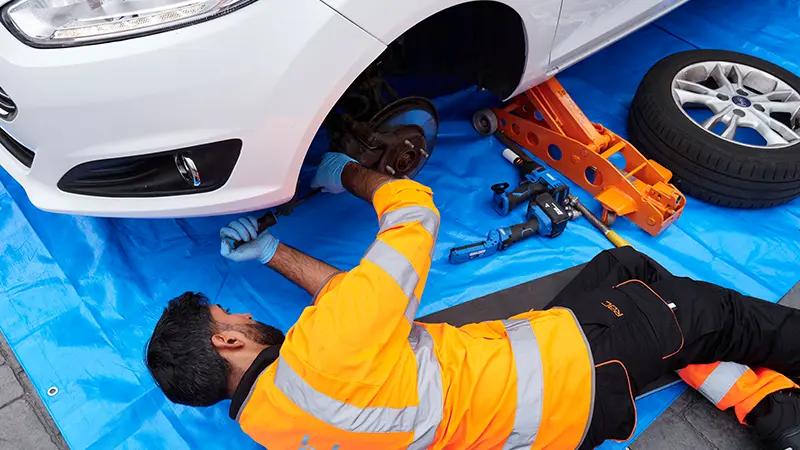 RAC Mobile Mechanic under the wheel arch of a white car