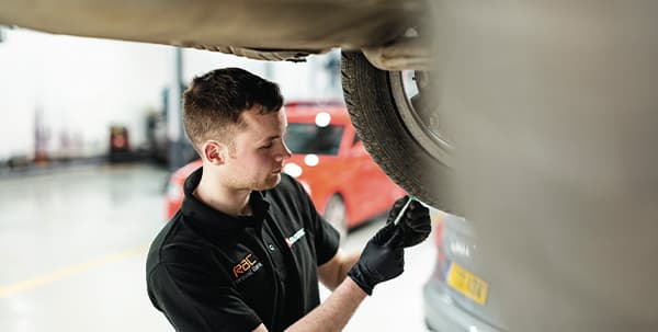 A mechanic inside a garage inspecting a vehicle