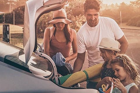 Young family putting things into a car boot