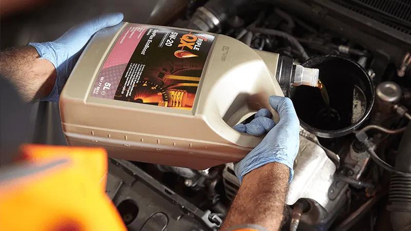 A close-up of somebody topping up a car vehicle's oil.