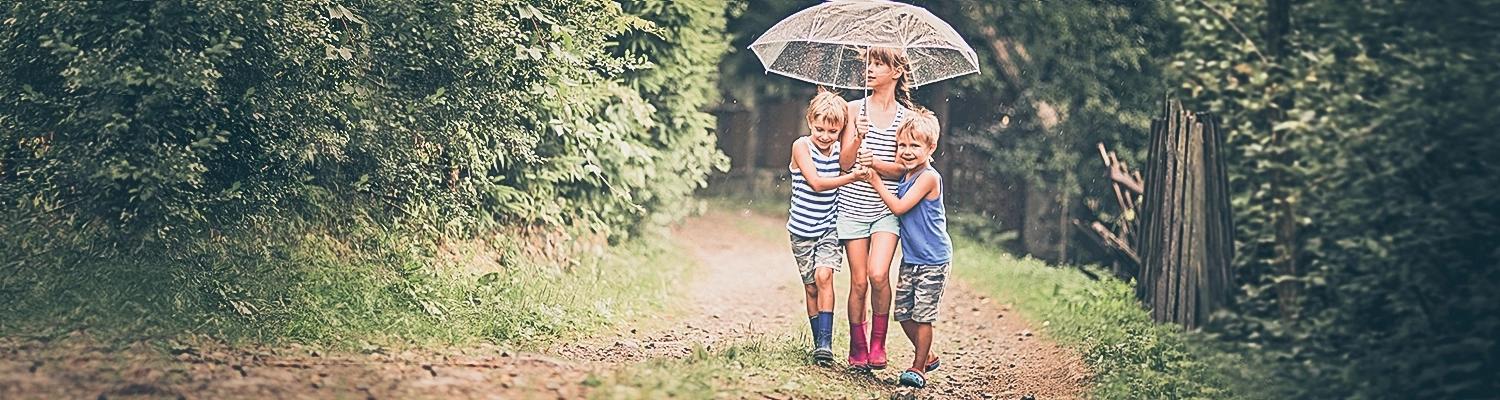 Three children walking under an umbrella