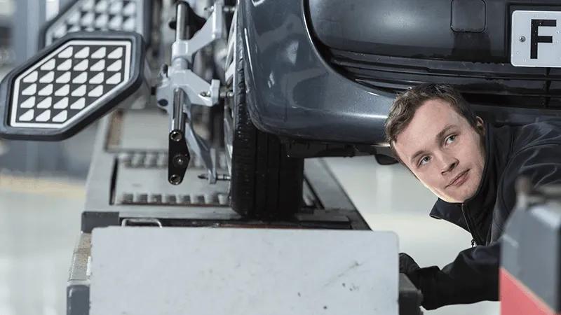 A mechanic inspecting the underside of a vehicle.