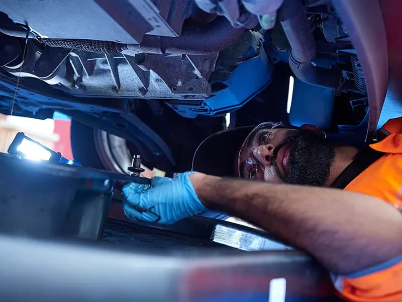 Close up of an RAC Mobile Mechanic underneath a car