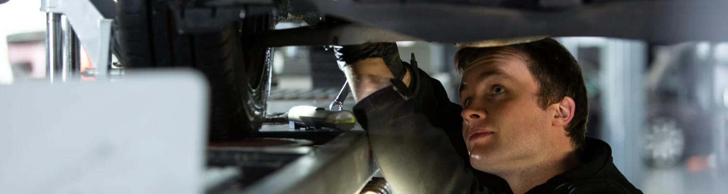 Mechanic looking at the underside of a car