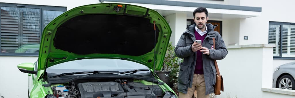Man stood outside his house next to his car that has the bonnet up