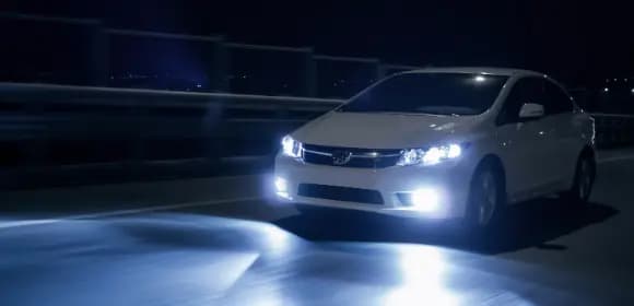 A car driving in the dark with headlights on