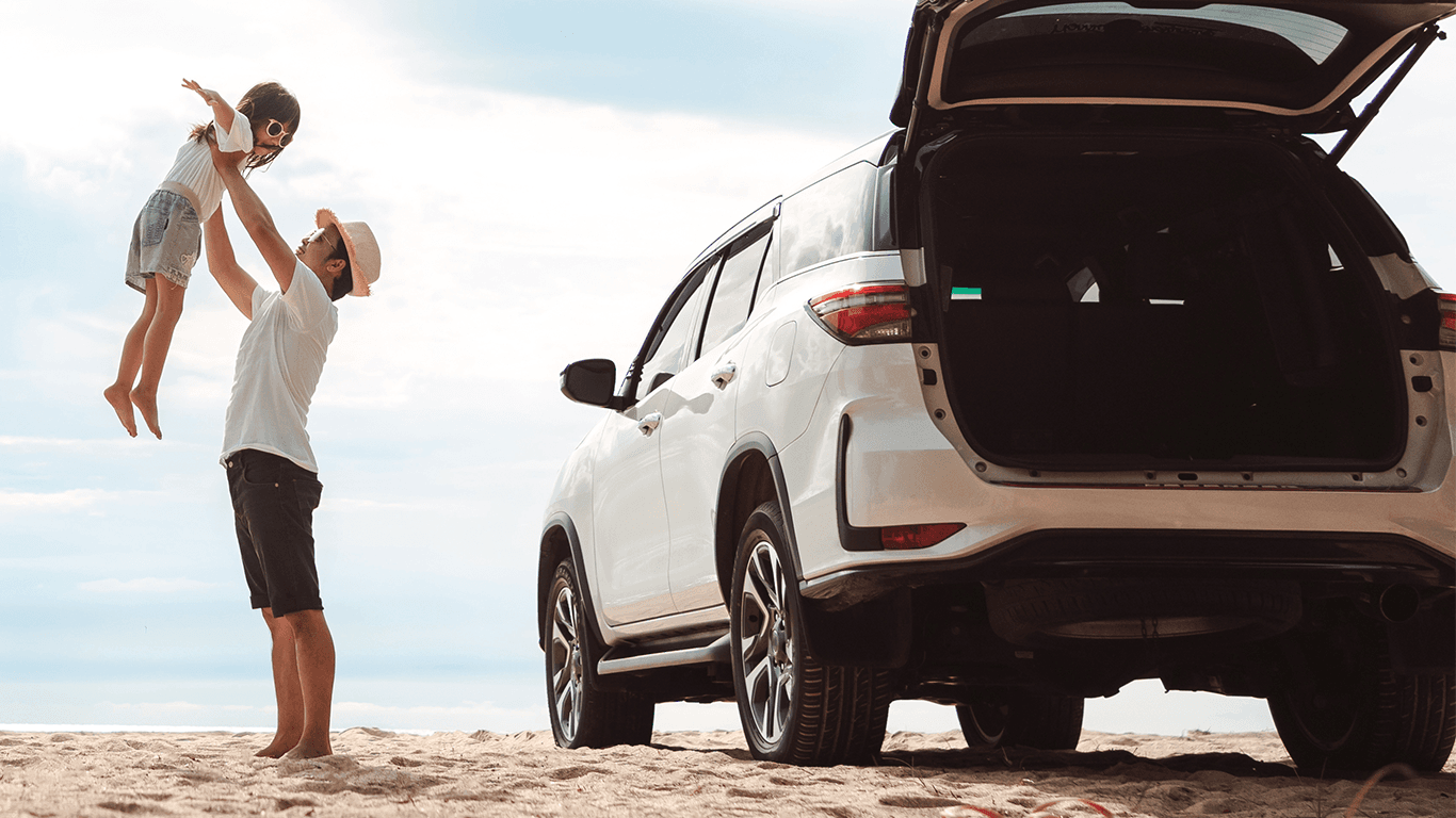 Father and daughter beside a car