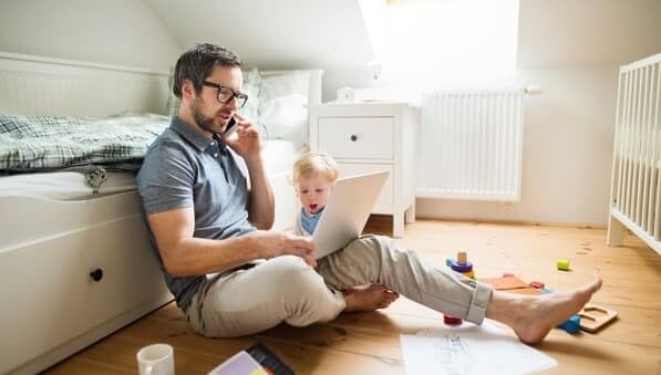 Man with a laptop on his lap with his son beside him