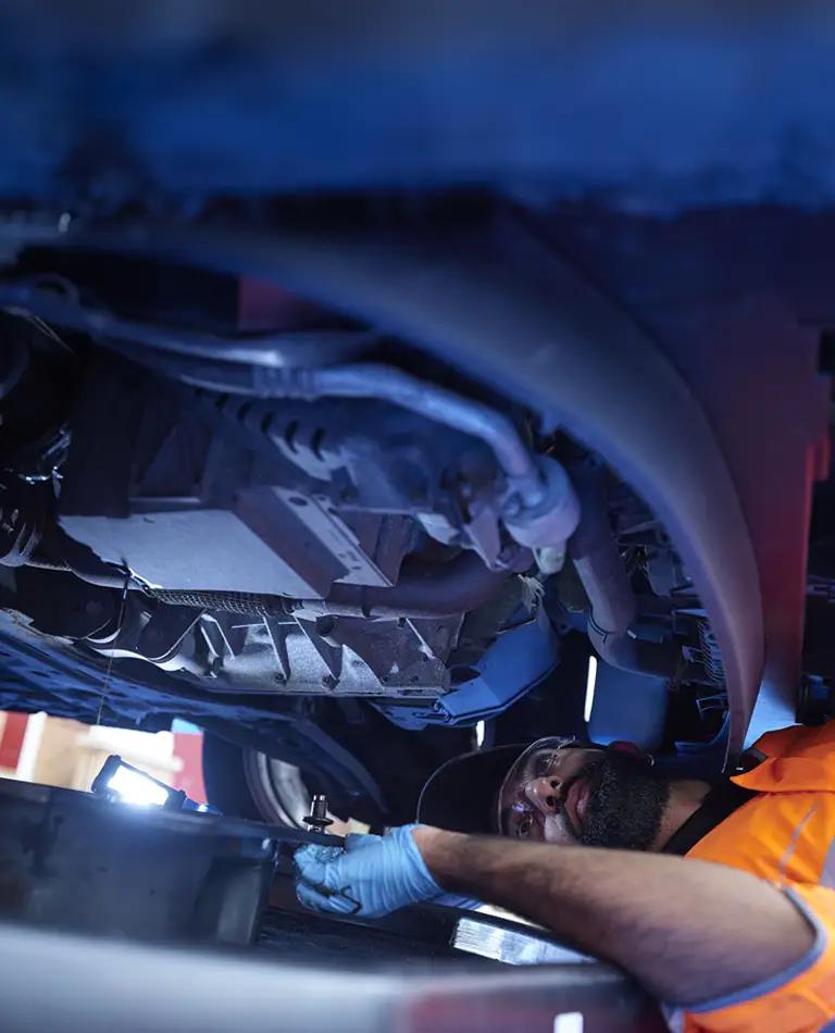 An RAC Mobile Mechanic inspecting the underside of a vehicle.