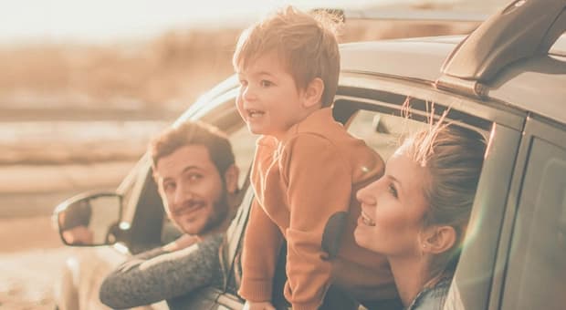Young family leaning out of a car window