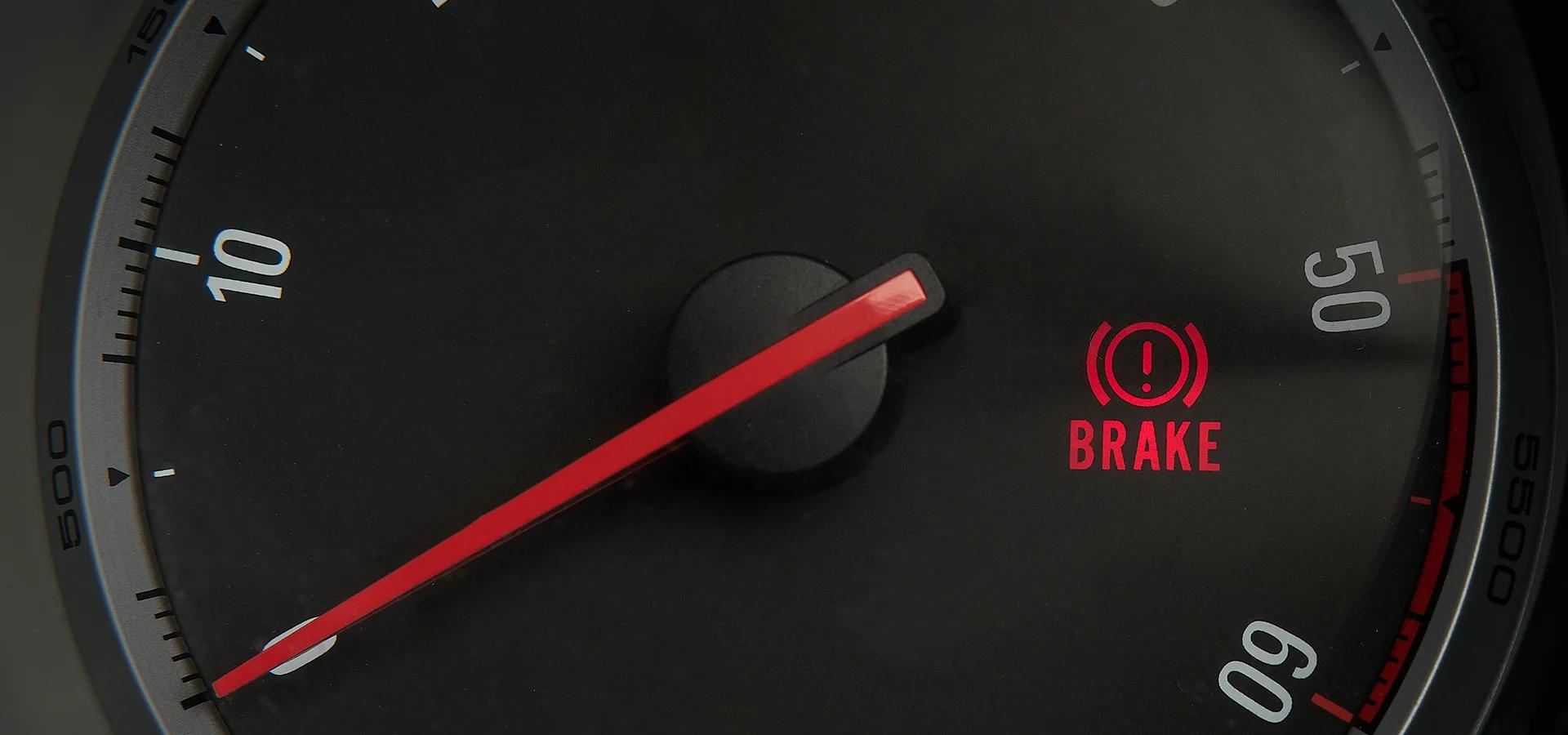 A close up of a car dashboard displaying a brake light warning