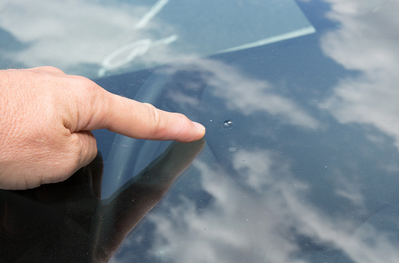 finger pointing to crack in windscreen